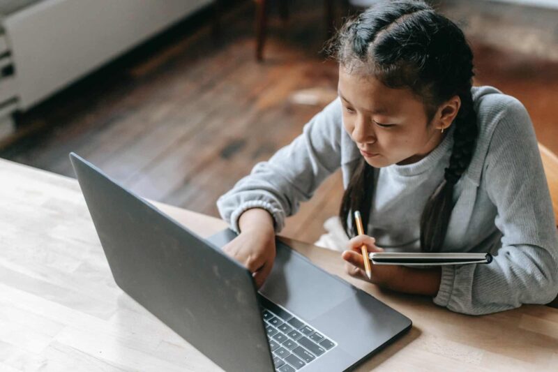 focused young asian girl studying on wireless laptop