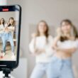 woman in white sleeveless shirt and blue denim skirt holding black smartphone