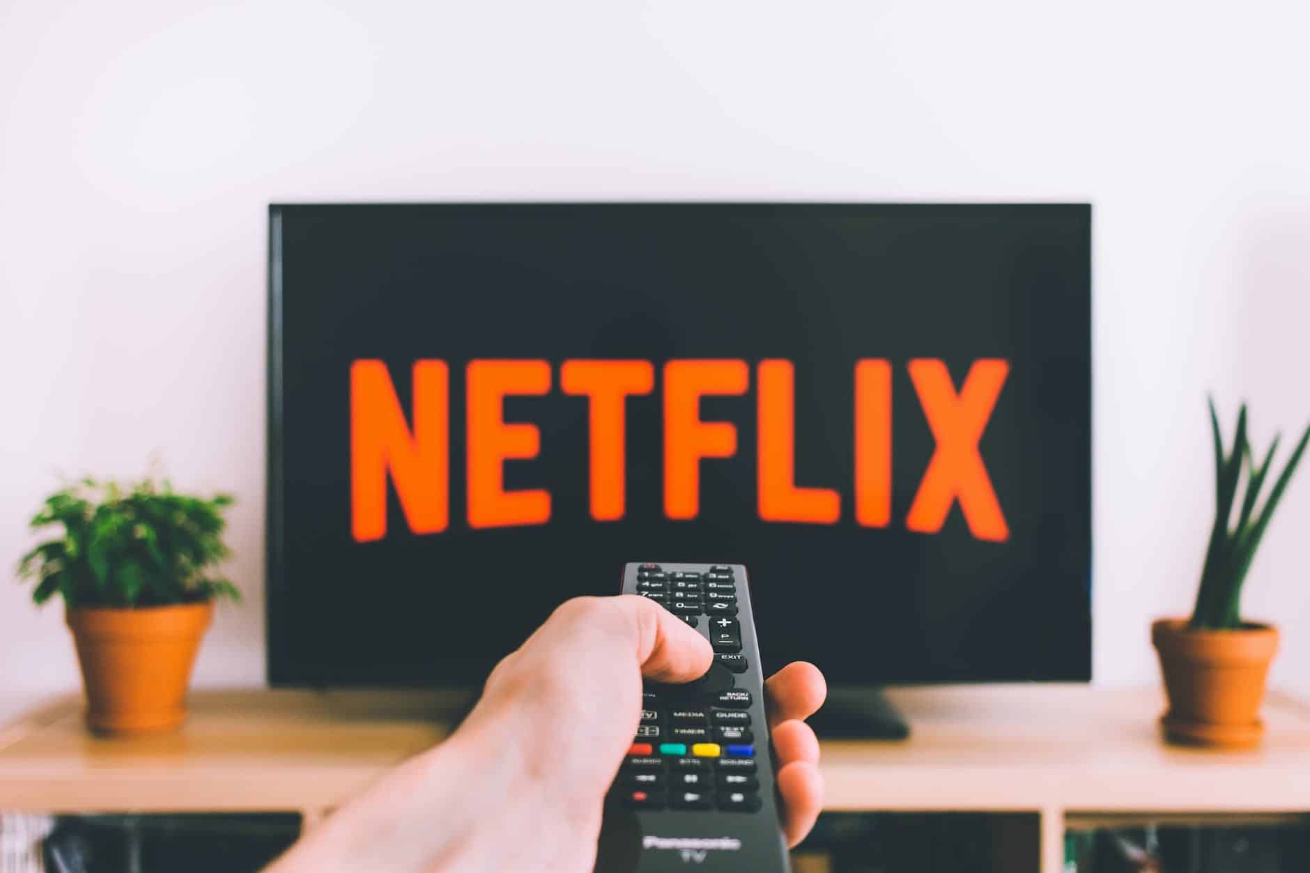 closeup photo of person holding panasonic remote control in front of turned on smart television